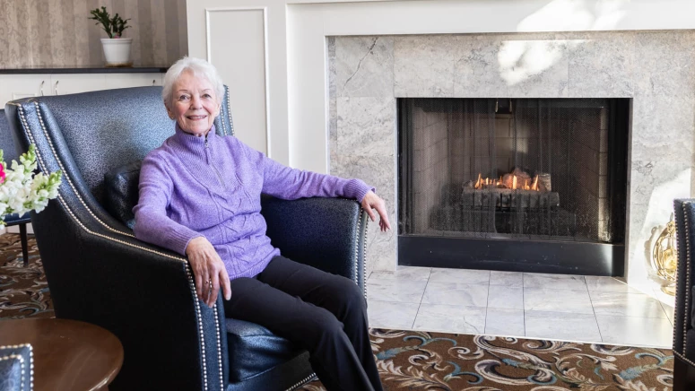 A woman sitting in a chair in front of a fireplace.